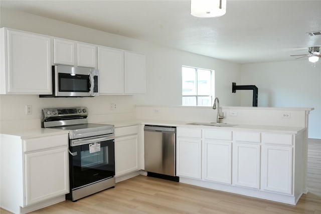 kitchen with light wood-type flooring, a sink, stainless steel appliances, a peninsula, and white cabinets