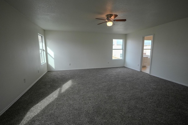 carpeted spare room featuring ceiling fan, baseboards, and a textured ceiling