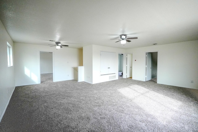 carpeted spare room with visible vents, a textured ceiling, and a ceiling fan