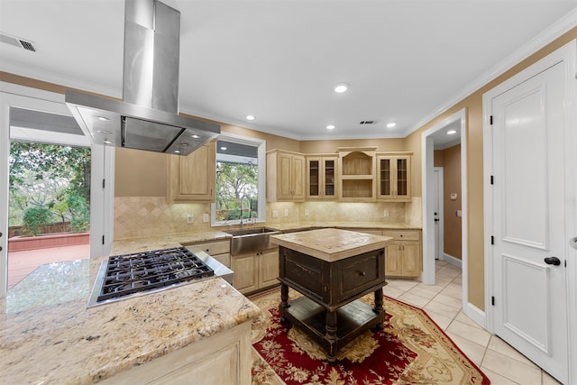 kitchen with light stone countertops, backsplash, light brown cabinetry, and island range hood