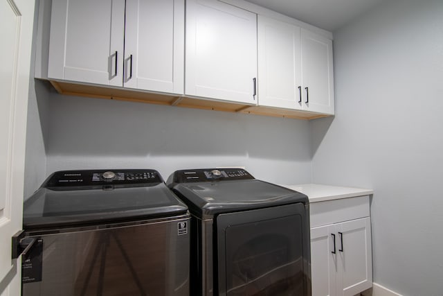 laundry area with independent washer and dryer and cabinets