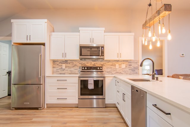 kitchen featuring appliances with stainless steel finishes, white cabinets, sink, and light hardwood / wood-style floors