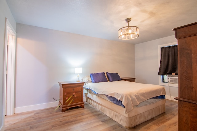 bedroom featuring cooling unit, a notable chandelier, and light wood-type flooring