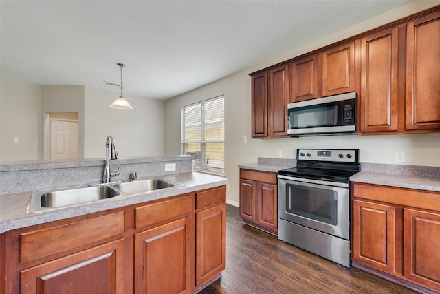 kitchen featuring appliances with stainless steel finishes, sink, decorative light fixtures, and dark hardwood / wood-style floors