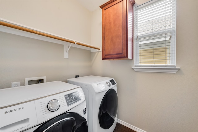 laundry area with washing machine and dryer, a healthy amount of sunlight, and cabinets