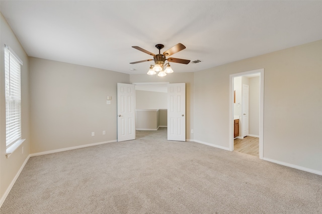 interior space featuring a walk in closet, a closet, ceiling fan, light carpet, and connected bathroom