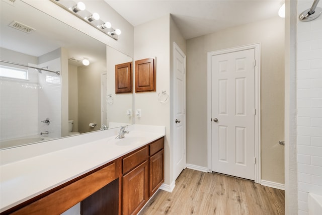 bathroom featuring visible vents, vanity, shower / tub combination, wood finished floors, and baseboards