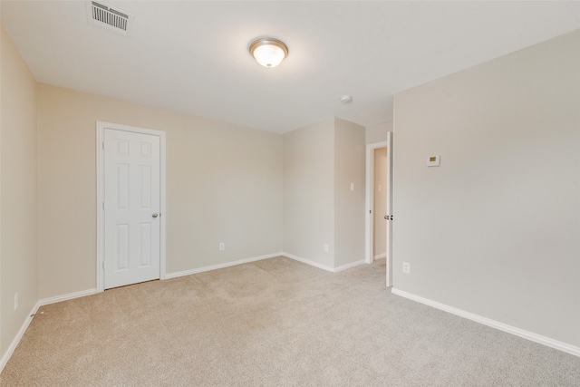 empty room featuring baseboards, visible vents, and light colored carpet