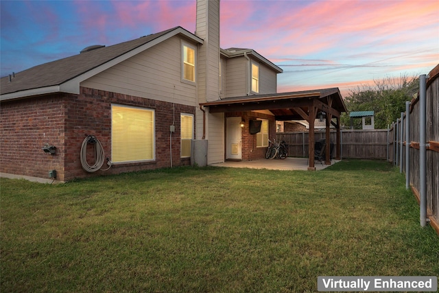 back house at dusk with a yard and a patio