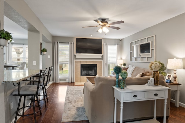 living room featuring dark hardwood / wood-style floors, a fireplace, and ceiling fan