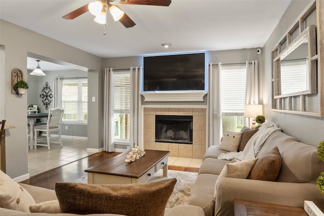 living room featuring a tiled fireplace, hardwood / wood-style flooring, and ceiling fan