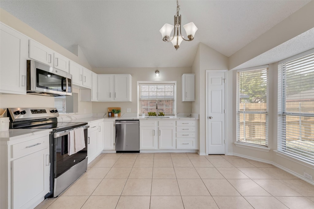 kitchen featuring white cabinets, appliances with stainless steel finishes, lofted ceiling, and a healthy amount of sunlight