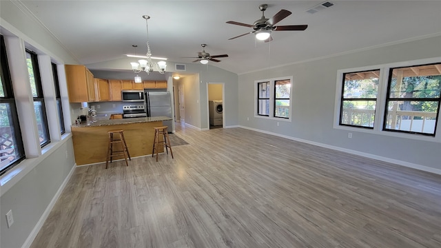 kitchen with washer / dryer, appliances with stainless steel finishes, light wood-type flooring, kitchen peninsula, and vaulted ceiling