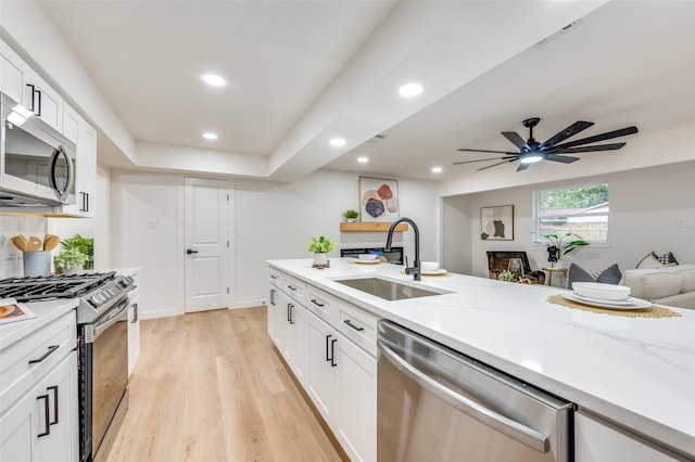 kitchen featuring light stone countertops, appliances with stainless steel finishes, sink, light hardwood / wood-style floors, and white cabinets