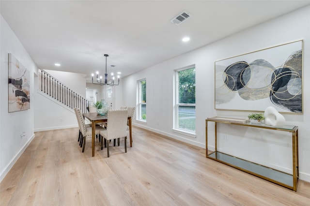 dining area with light hardwood / wood-style flooring and a notable chandelier