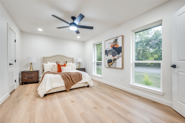 bedroom with multiple windows, light hardwood / wood-style floors, and ceiling fan