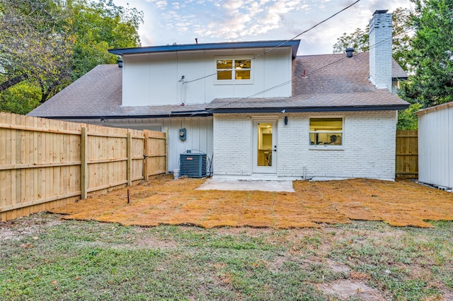 rear view of property featuring a patio, cooling unit, and a lawn