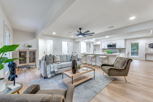 living room with light hardwood / wood-style floors, sink, and ceiling fan