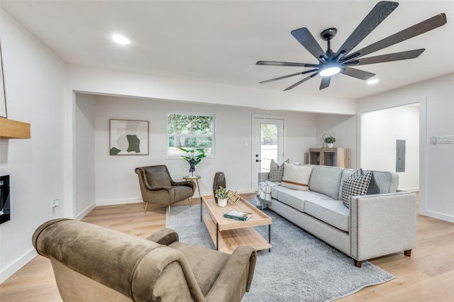 living room with light hardwood / wood-style floors, electric panel, and ceiling fan