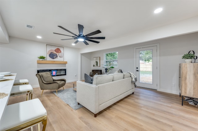 living room with ceiling fan and light hardwood / wood-style flooring