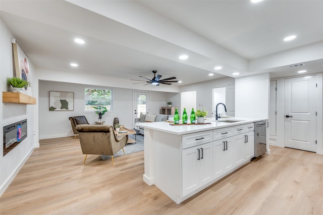 kitchen with an island with sink, ceiling fan, light hardwood / wood-style floors, stainless steel dishwasher, and white cabinets