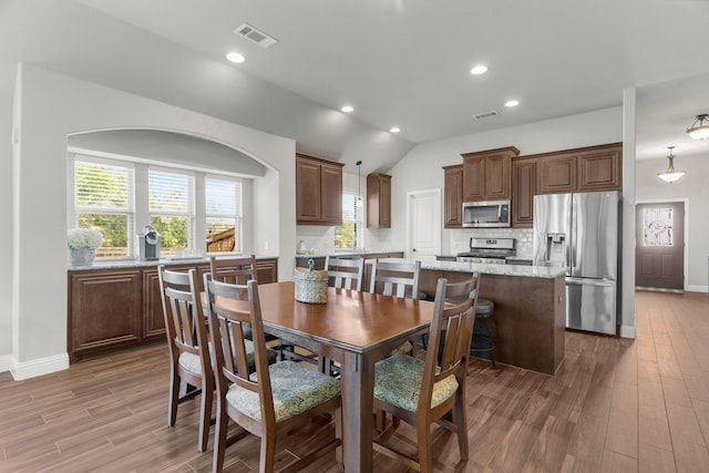 dining area featuring hardwood / wood-style flooring and vaulted ceiling