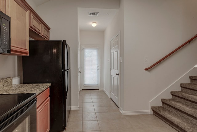 kitchen featuring light stone countertops, black appliances, and light tile patterned floors