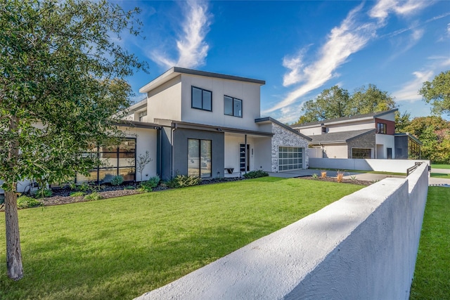 contemporary house featuring stucco siding, concrete driveway, an attached garage, a front yard, and fence