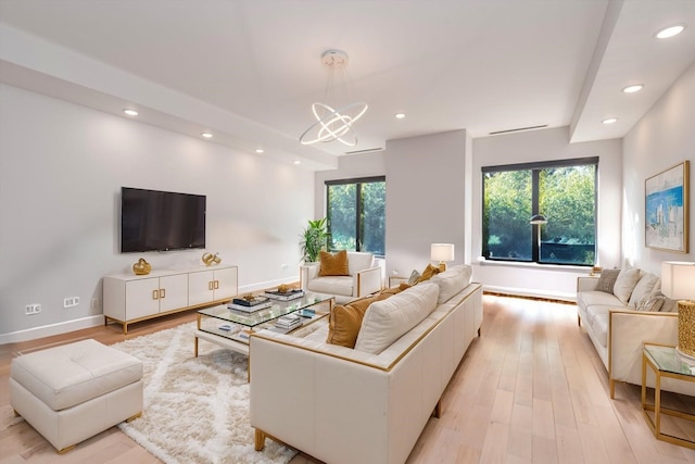 living room with a chandelier, a wealth of natural light, and light wood-type flooring