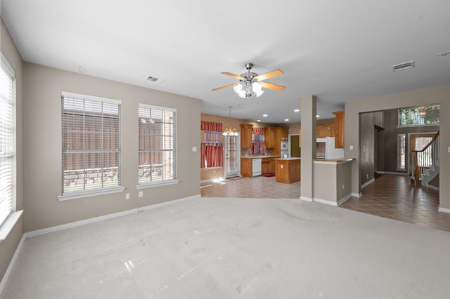 unfurnished living room featuring light carpet and ceiling fan with notable chandelier