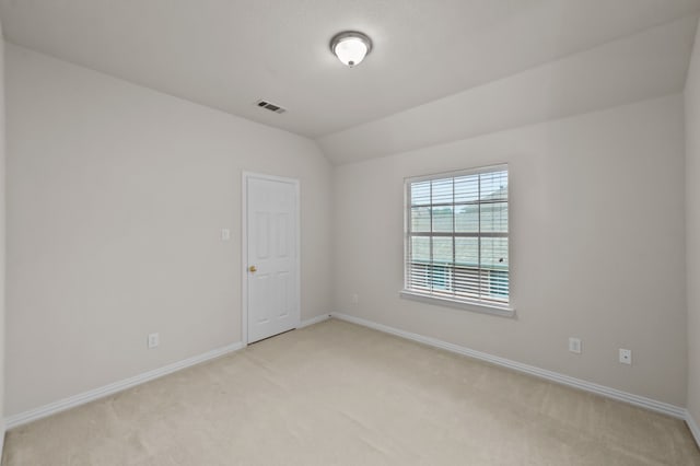 carpeted empty room featuring lofted ceiling