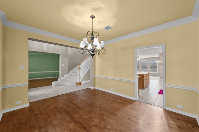 unfurnished room featuring wood-type flooring, ornamental molding, and ceiling fan with notable chandelier