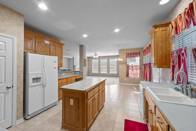 kitchen with white appliances, sink, a center island, light tile patterned floors, and ceiling fan with notable chandelier