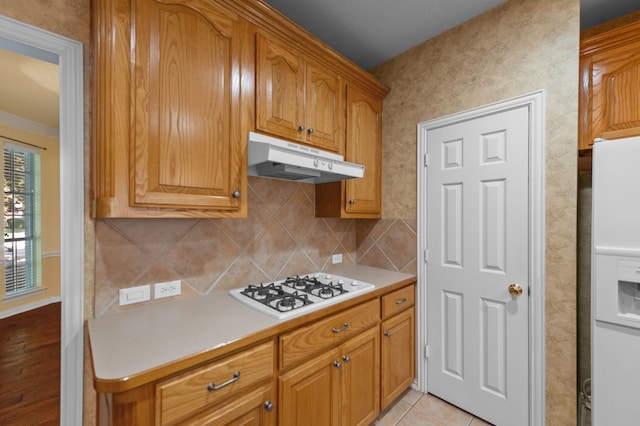 kitchen featuring white appliances, decorative backsplash, and light tile patterned flooring