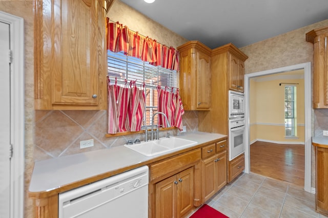 kitchen with light tile patterned flooring, sink, backsplash, and white appliances