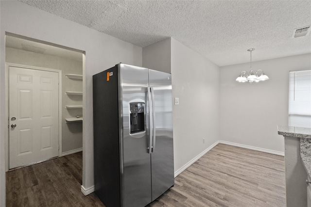 kitchen featuring hardwood / wood-style flooring, hanging light fixtures, a textured ceiling, and stainless steel refrigerator with ice dispenser