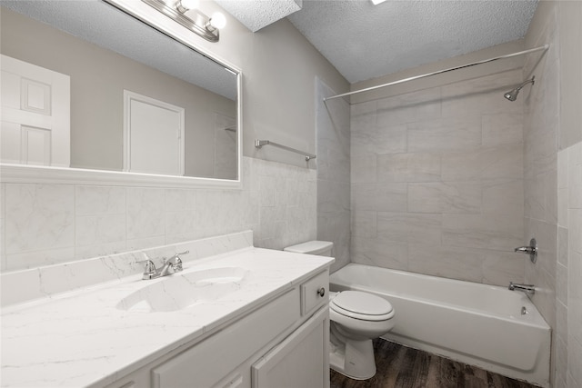 full bathroom featuring wood-type flooring, a textured ceiling, toilet, tiled shower / bath, and vanity