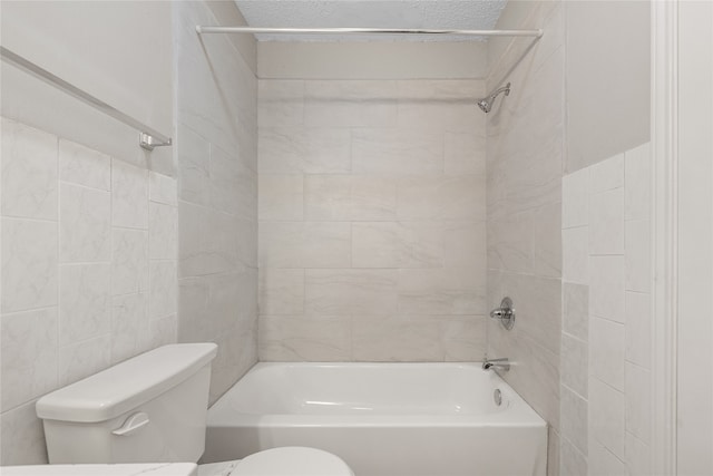 bathroom featuring tiled shower / bath, tile walls, and toilet