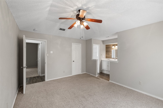 unfurnished bedroom featuring a textured ceiling, carpet floors, and ceiling fan