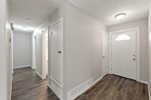 foyer entrance with dark hardwood / wood-style floors and a textured ceiling