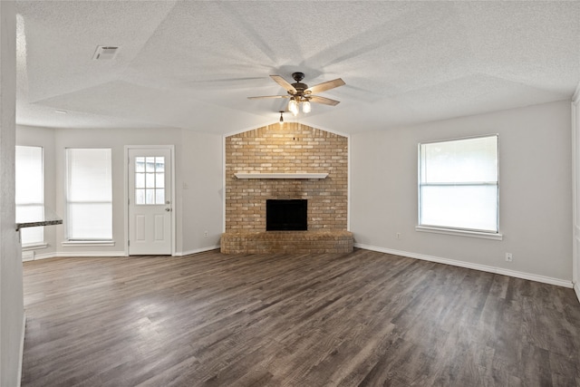 unfurnished living room with lofted ceiling, dark wood-type flooring, a textured ceiling, a fireplace, and ceiling fan