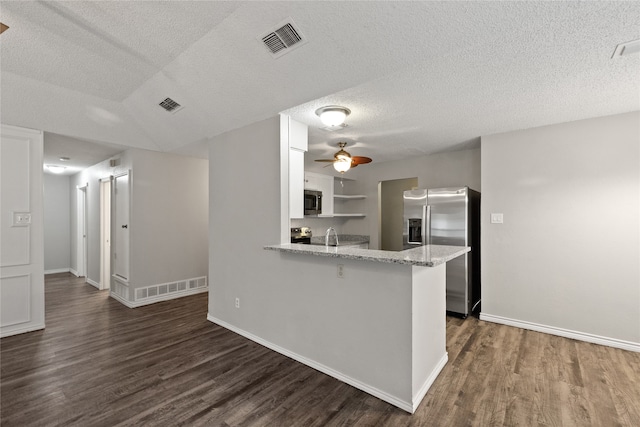 kitchen with kitchen peninsula, white cabinetry, a textured ceiling, dark wood-type flooring, and stainless steel appliances