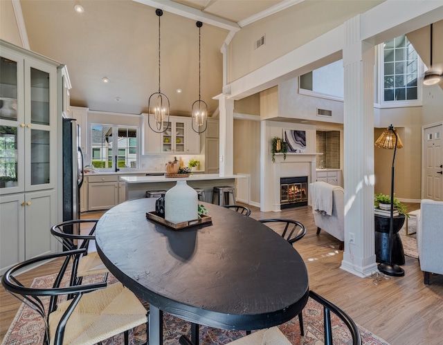 dining room with crown molding, a towering ceiling, and light wood-type flooring