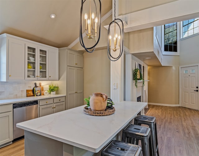 kitchen with a breakfast bar, light hardwood / wood-style flooring, a kitchen island, and stainless steel dishwasher