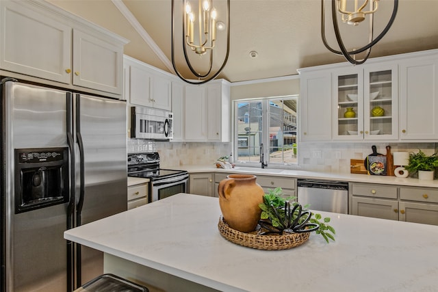 kitchen with white cabinets, decorative light fixtures, appliances with stainless steel finishes, and vaulted ceiling