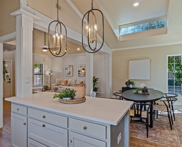 kitchen with light stone countertops, dark wood-type flooring, crown molding, decorative light fixtures, and a kitchen island