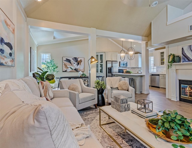 living room with light wood-type flooring, high vaulted ceiling, and a chandelier