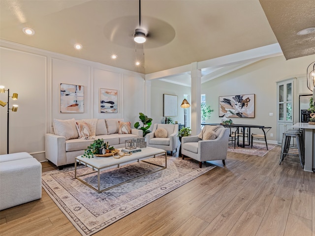 living room with ceiling fan with notable chandelier, lofted ceiling, a wealth of natural light, and light hardwood / wood-style flooring