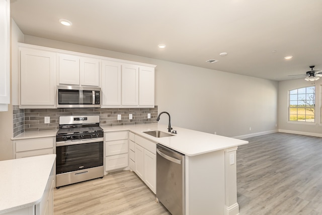 kitchen featuring appliances with stainless steel finishes, kitchen peninsula, white cabinetry, and light hardwood / wood-style flooring