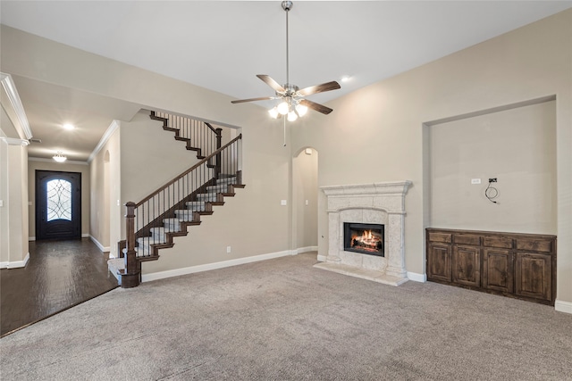 unfurnished living room featuring carpet flooring, ceiling fan, a fireplace, and ornamental molding